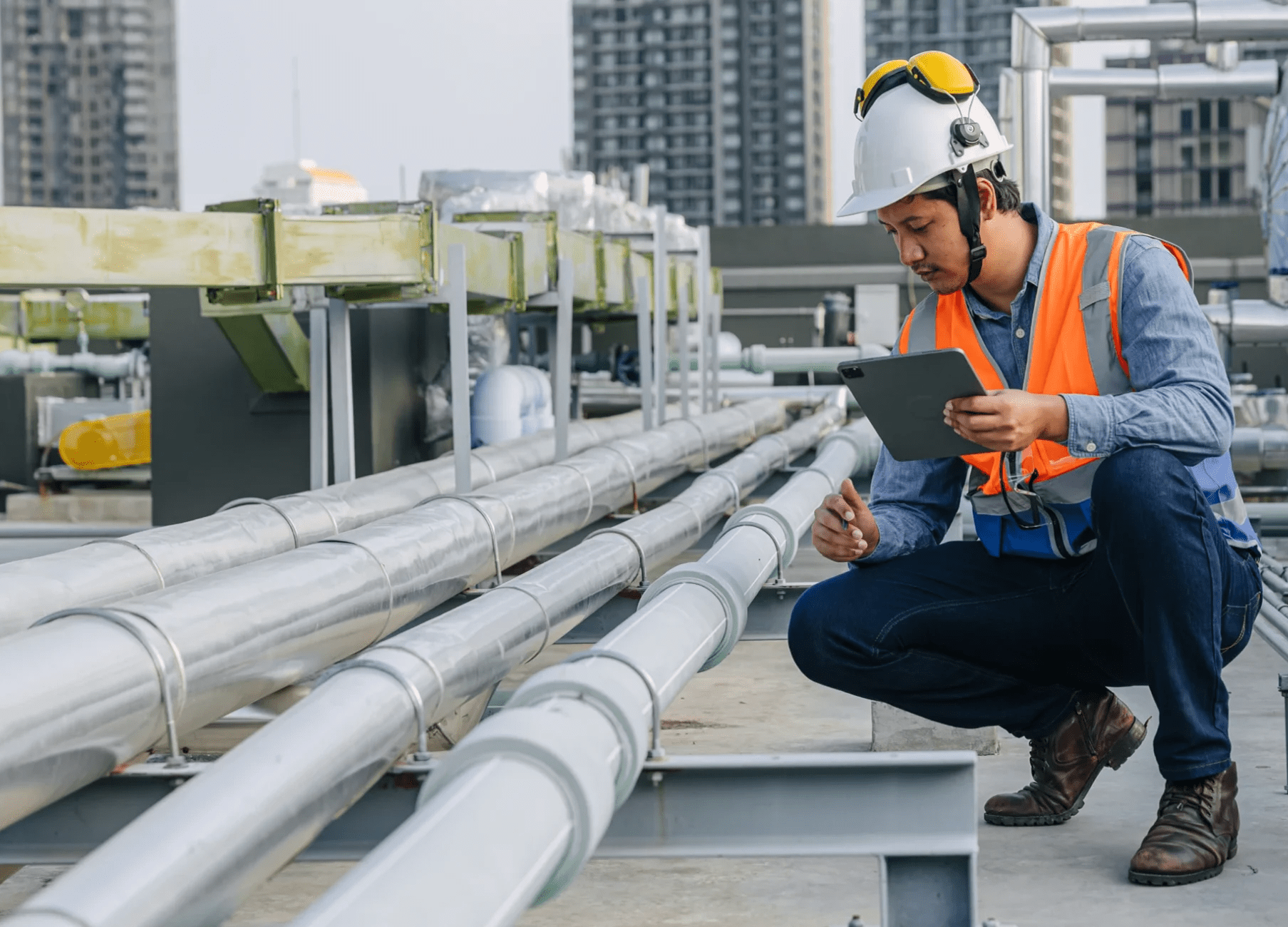 Engineer inspecting rooftop pipes with tablet