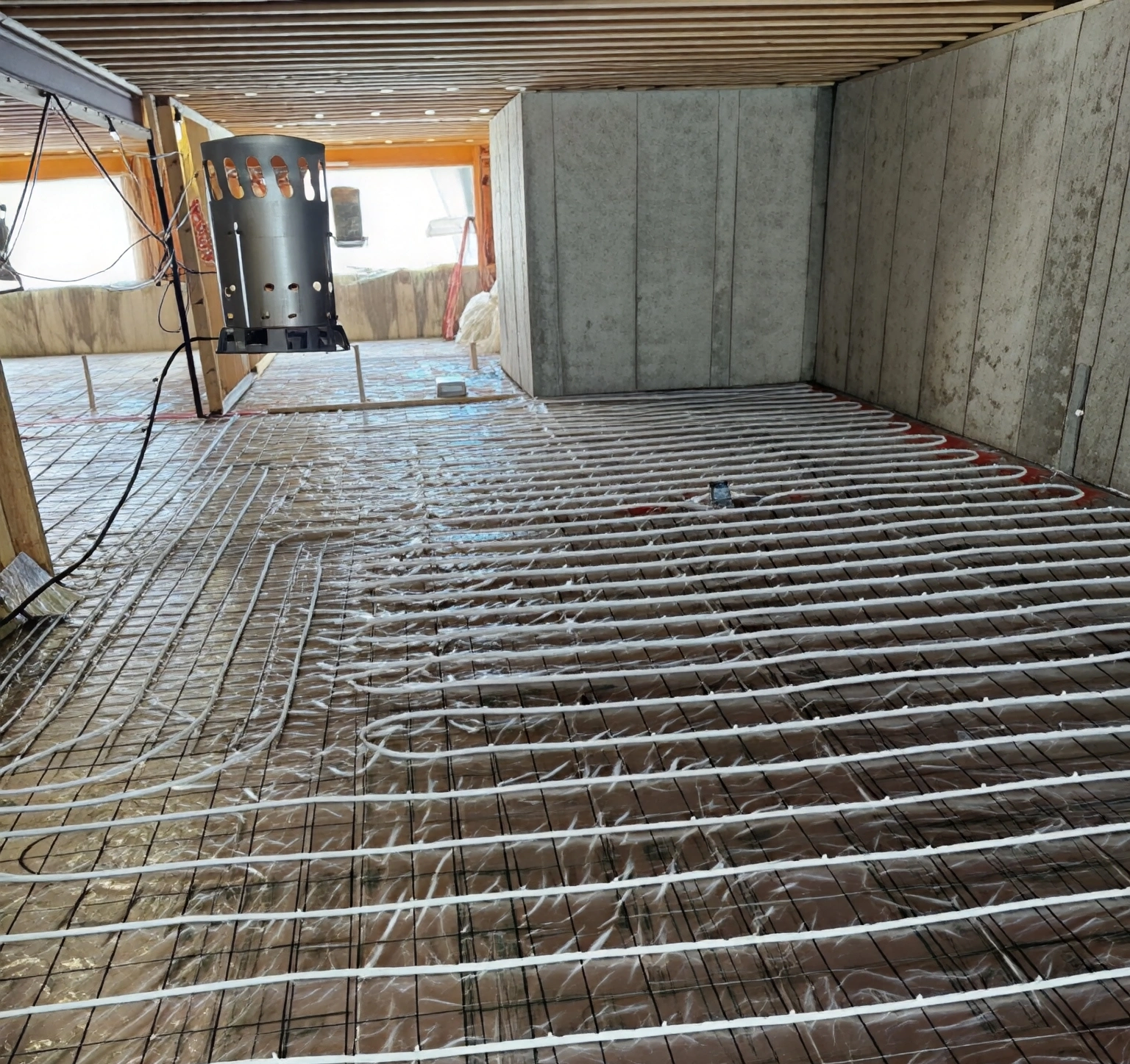 Underfloor heating pipes being installed on a concrete floor.