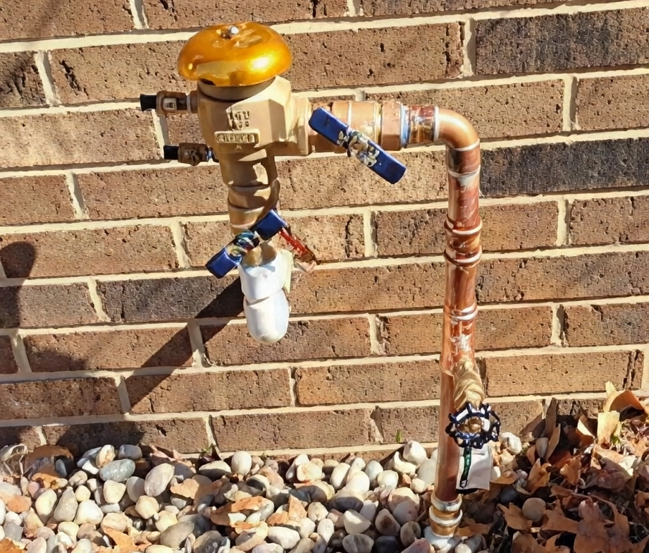 Outdoor water faucet with attached hose splitter and shut-off valves.